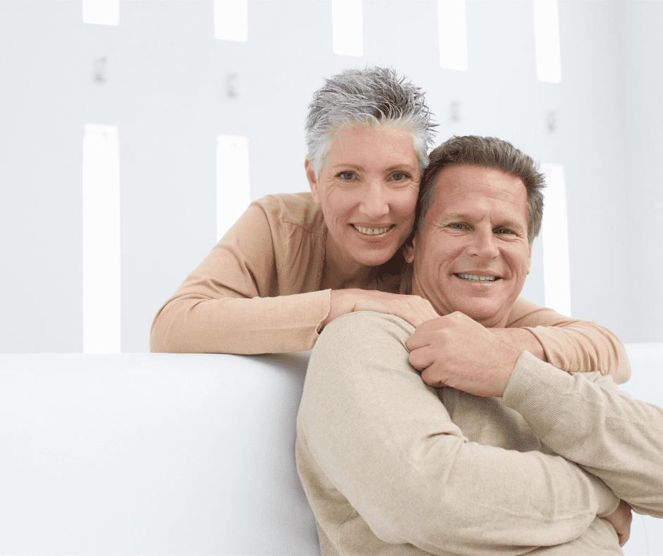 A content mature couple embracing, with smiles that suggest satisfaction with their dental care including affordable dentures and wisdom teeth extractions.