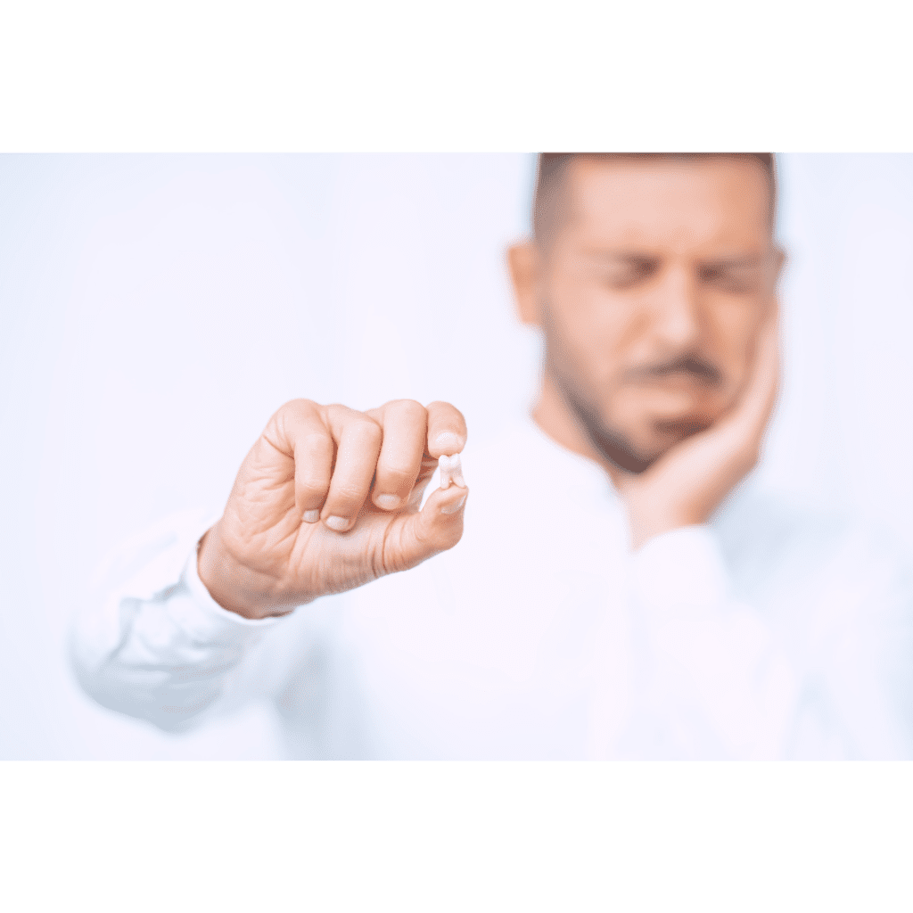 Man holding a broken tooth and suffering from dental pain, highlighting the emergency repair services at The Denture Company in Nampa, Idaho.